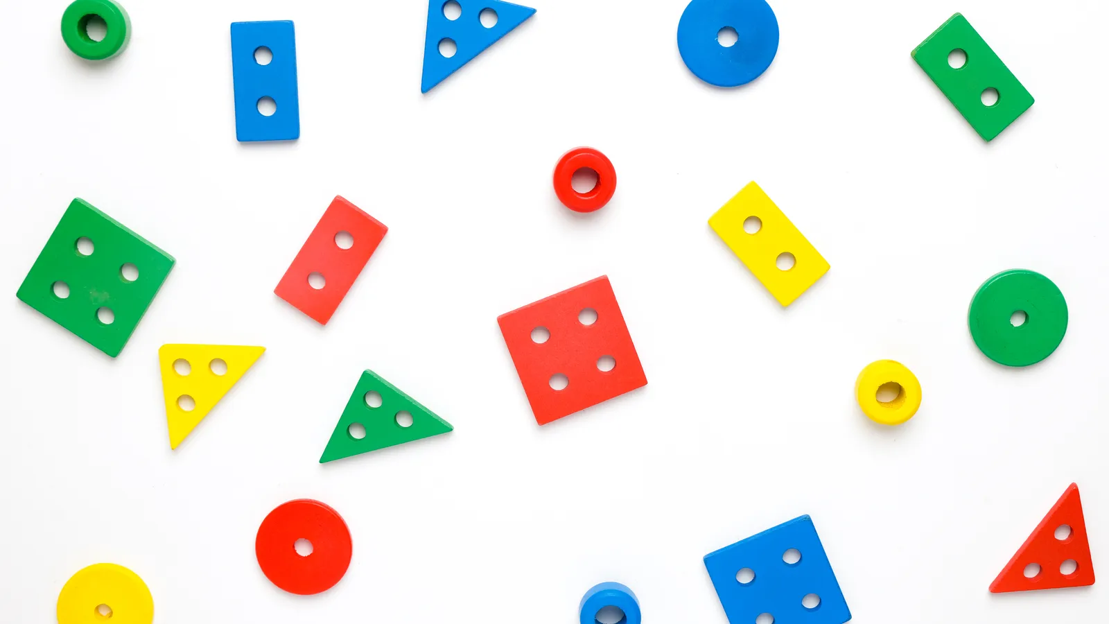 Flat lay of wooden shape-sorting toys on a white background