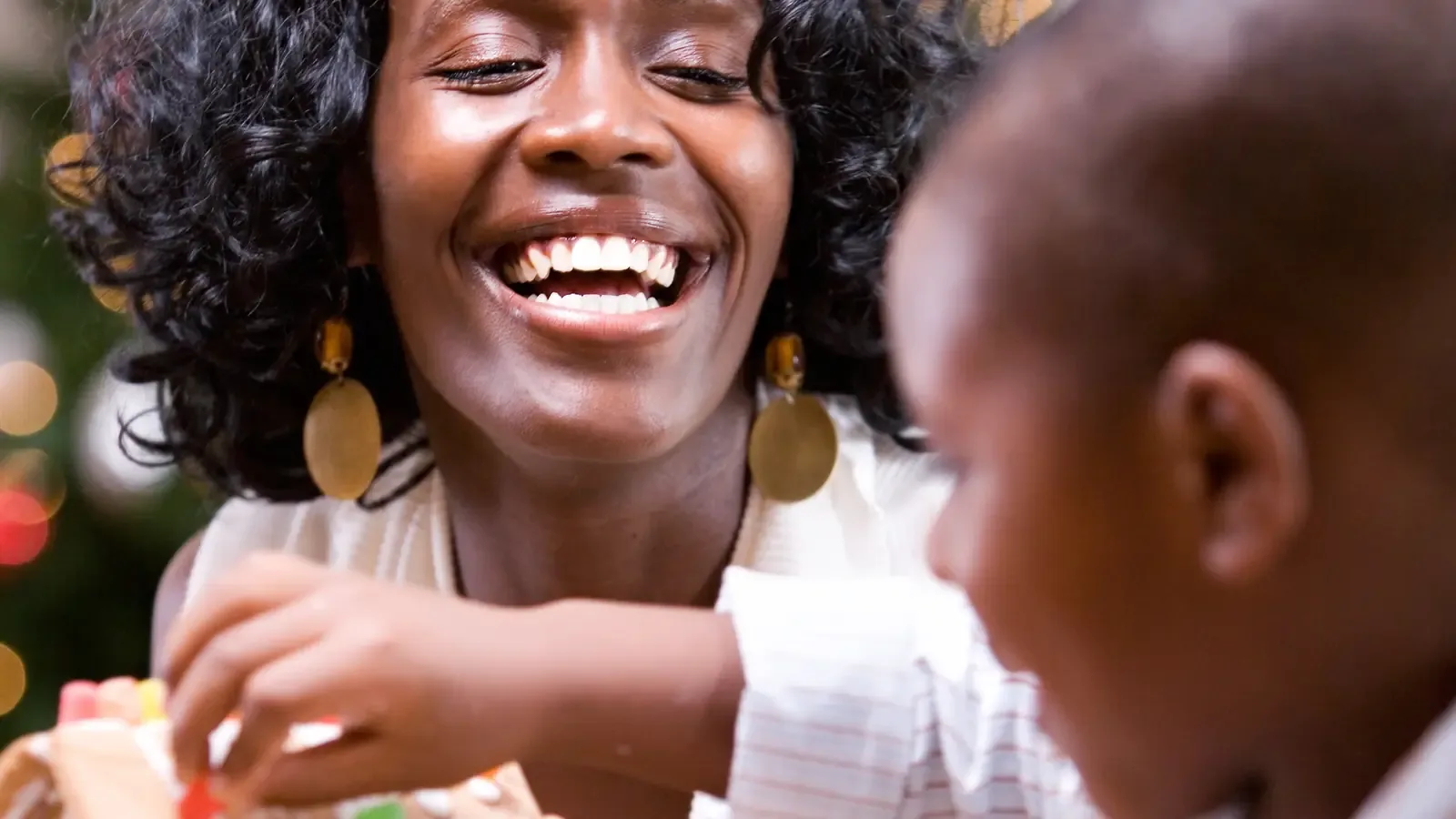 A parent and child building a holiday gingerbread house together at a kitchen table