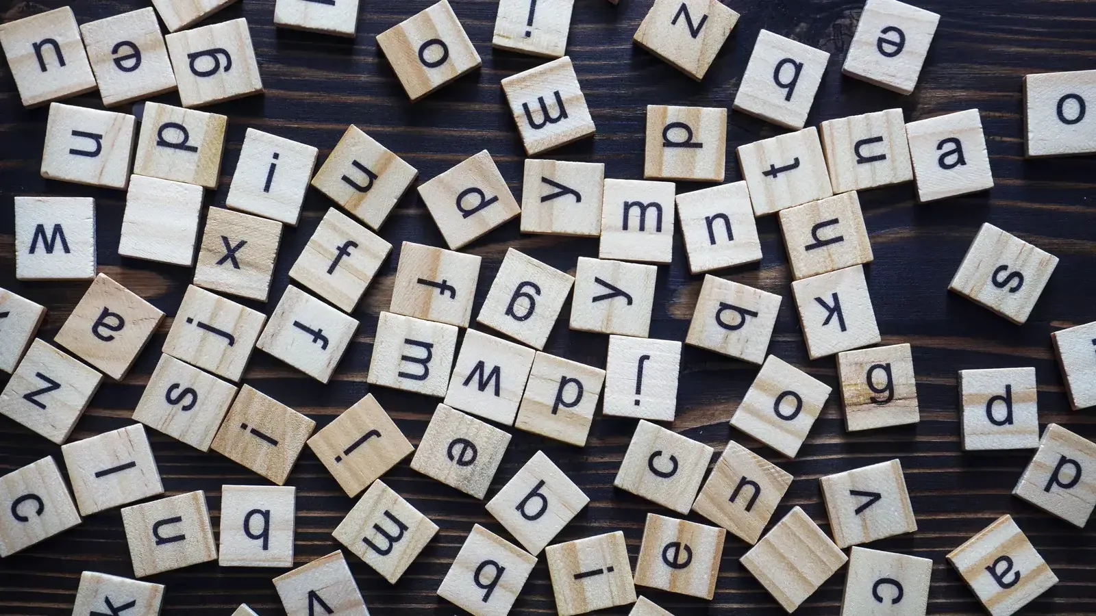 Wooden scrabble-style letter tiles spelling out alphabet letters