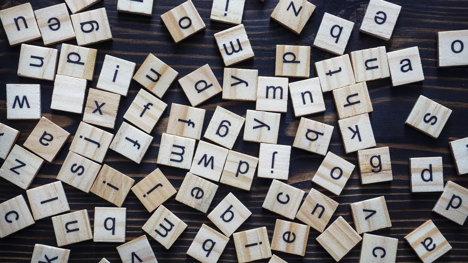 Wooden scrabble-style letter tiles spelling out alphabet letters
