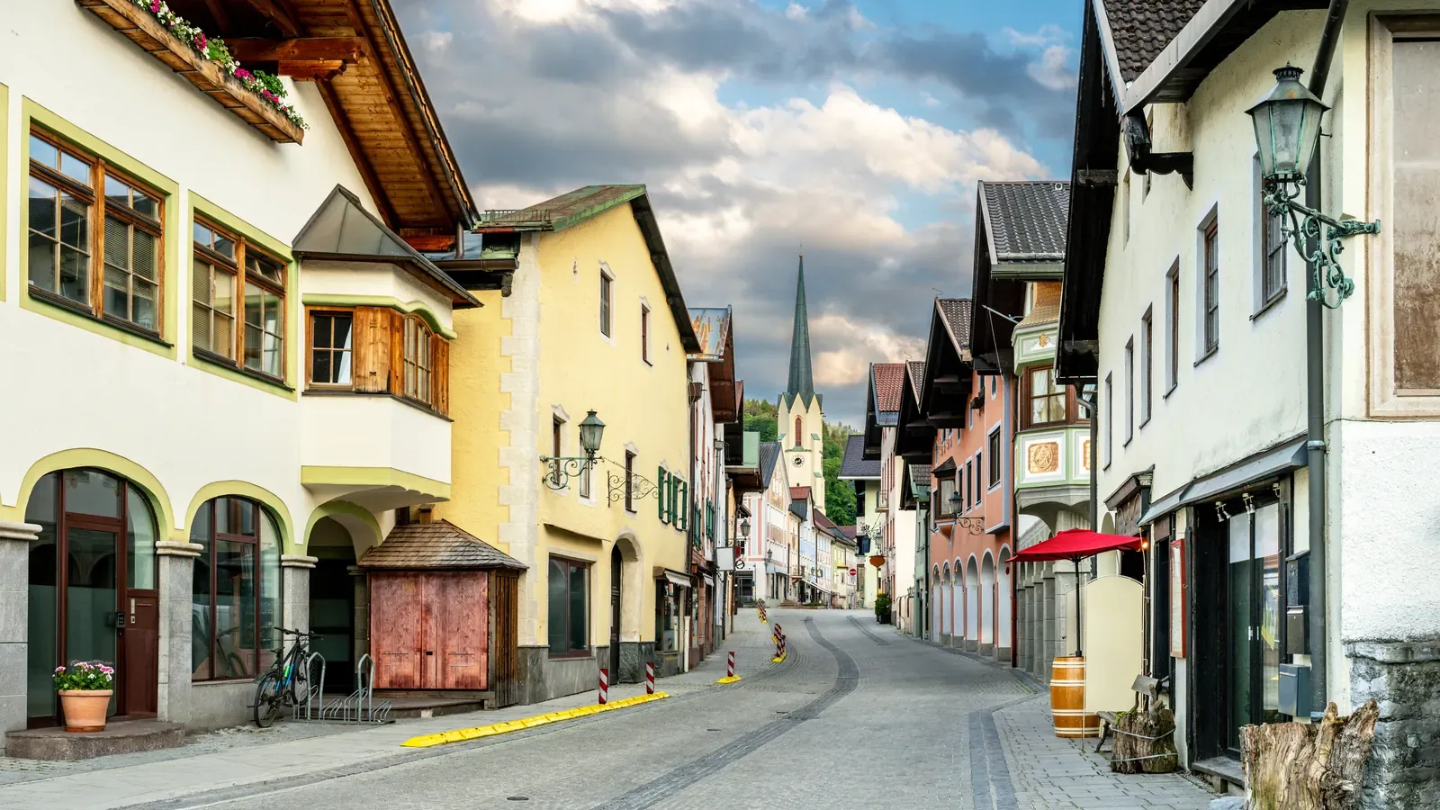 A street of painted historic buildings in a Bavarian town with mountains behind