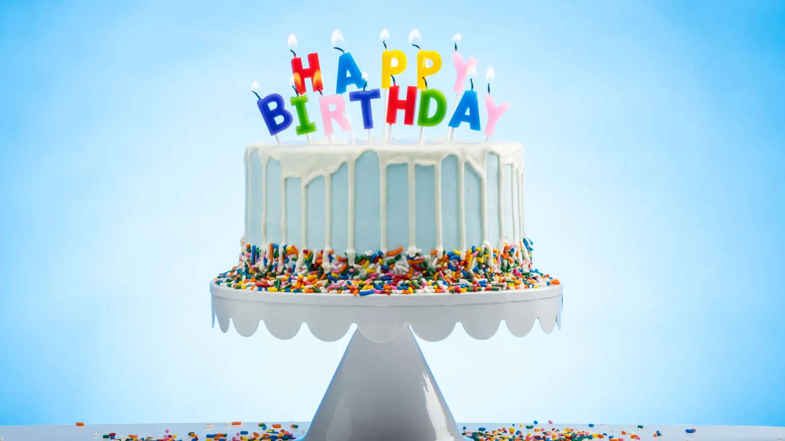 Decorated birthday cake with candles on a plain background