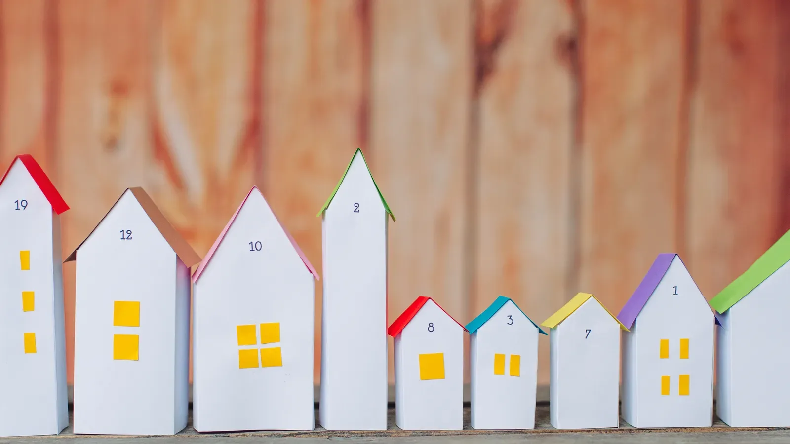 Numbered paper house advent calendar lined up on a wooden background