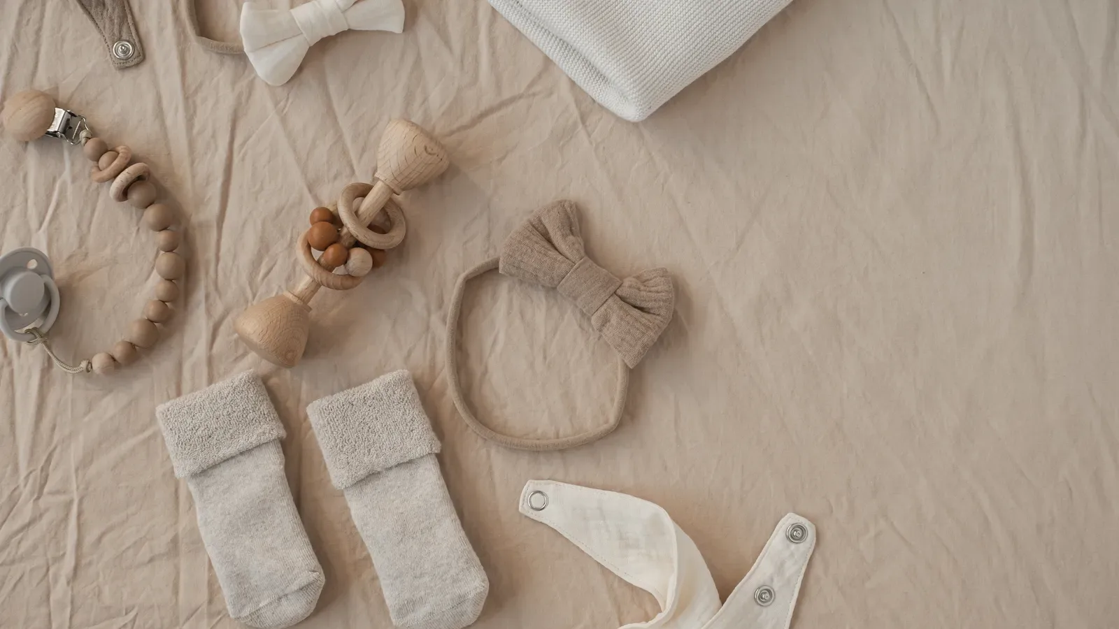 Flat lay of neutral baby clothes, toys and accessories arranged as a handmade gift set