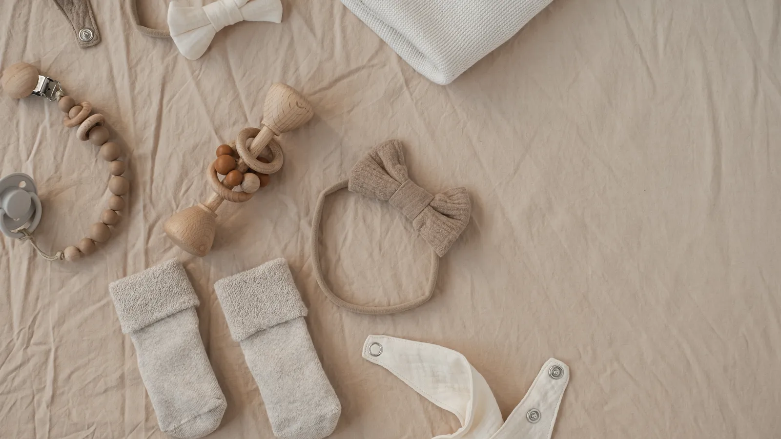 Flat lay of neutral baby clothes, toys and accessories arranged as a handmade gift set