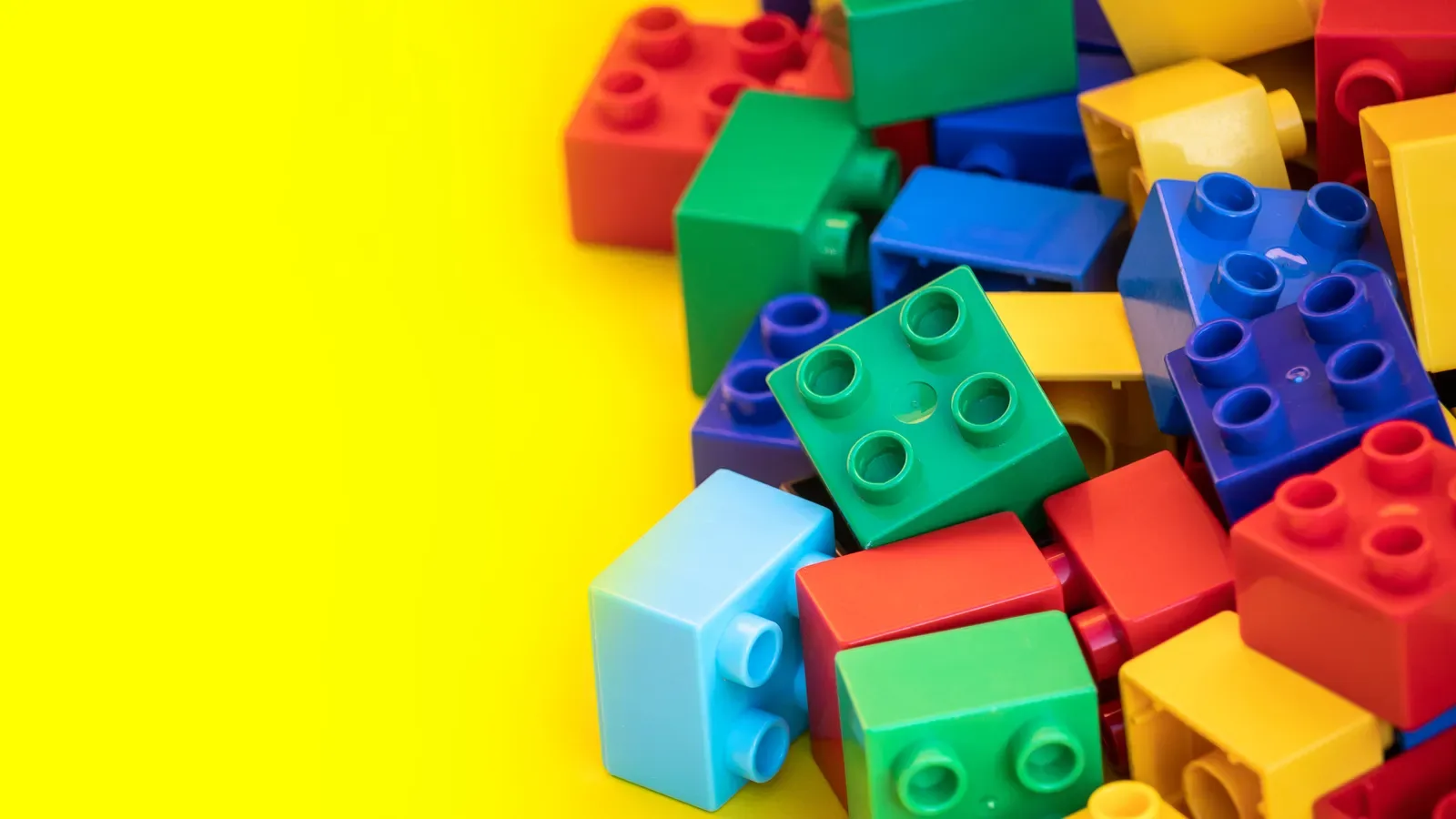 Colorful building blocks and construction toys arranged on a plain background