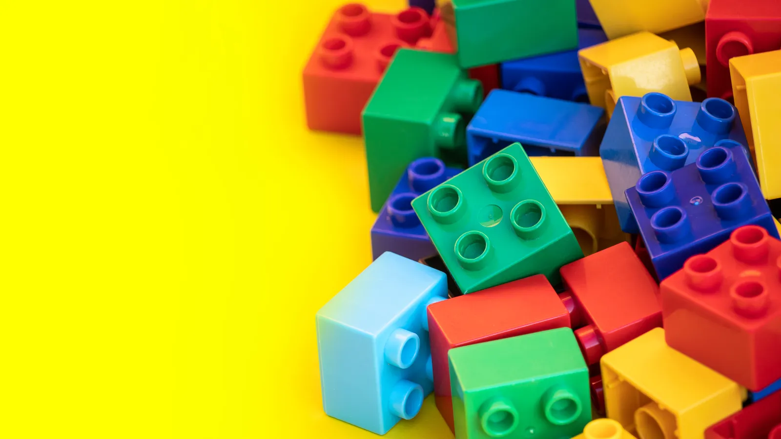 Colourful building blocks and construction toys arranged on a plain background