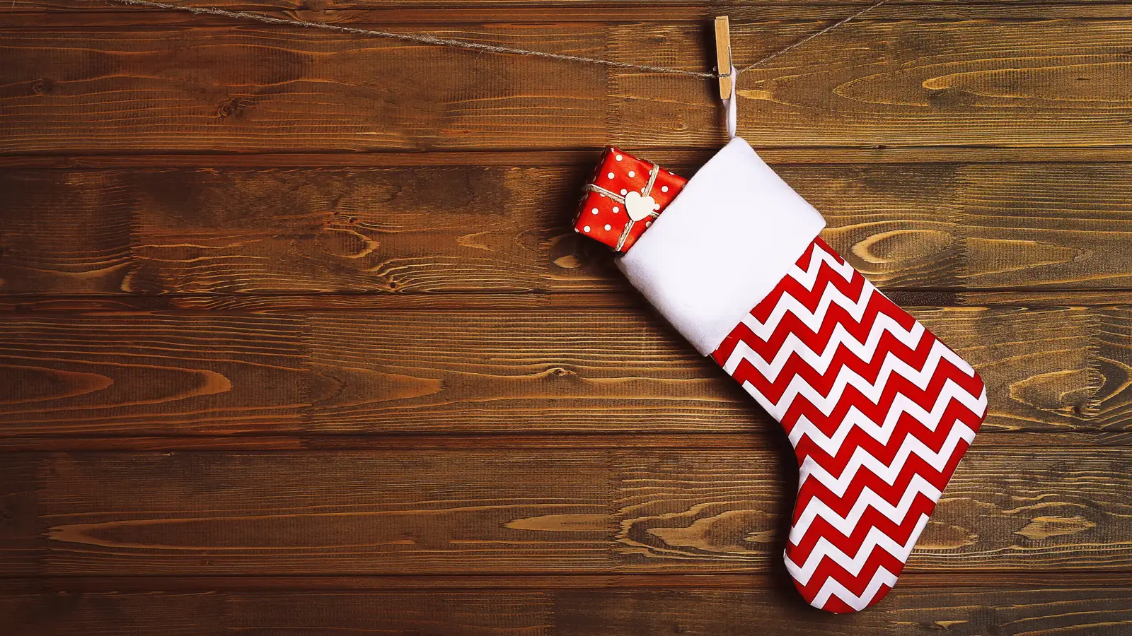Red and white chevron Christmas stocking hanging on a dark wooden wall