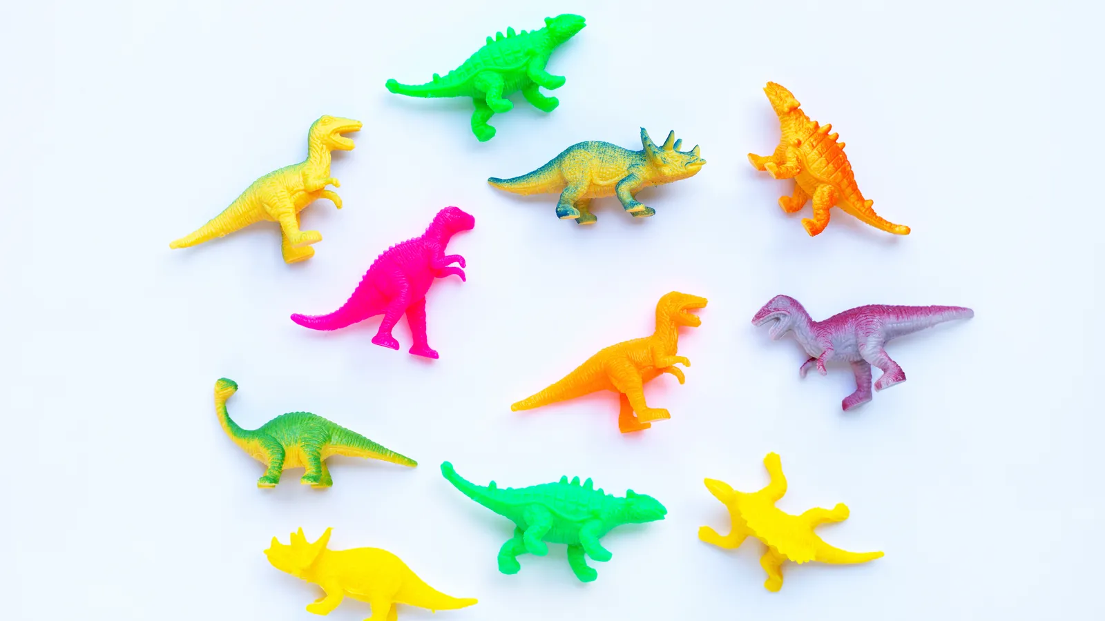 Plastic dinosaur toys arranged on a plain background for a party theme